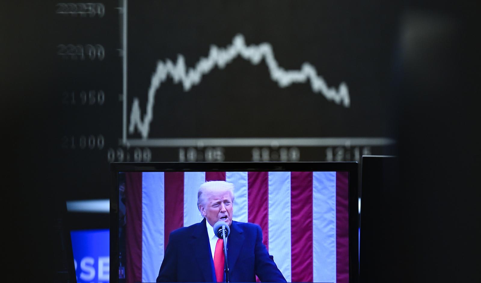 03 April 2025, Hesse, Frankfurt/Main: Behind a television monitor showing US President Donald Trump, the display board with the Dax curve shows falling share prices. The tariff package announced by US President Trump has pushed share prices sharply into negative territory. Photo: Arne Dedert/dpa Photo: Arne Dedert/DPA