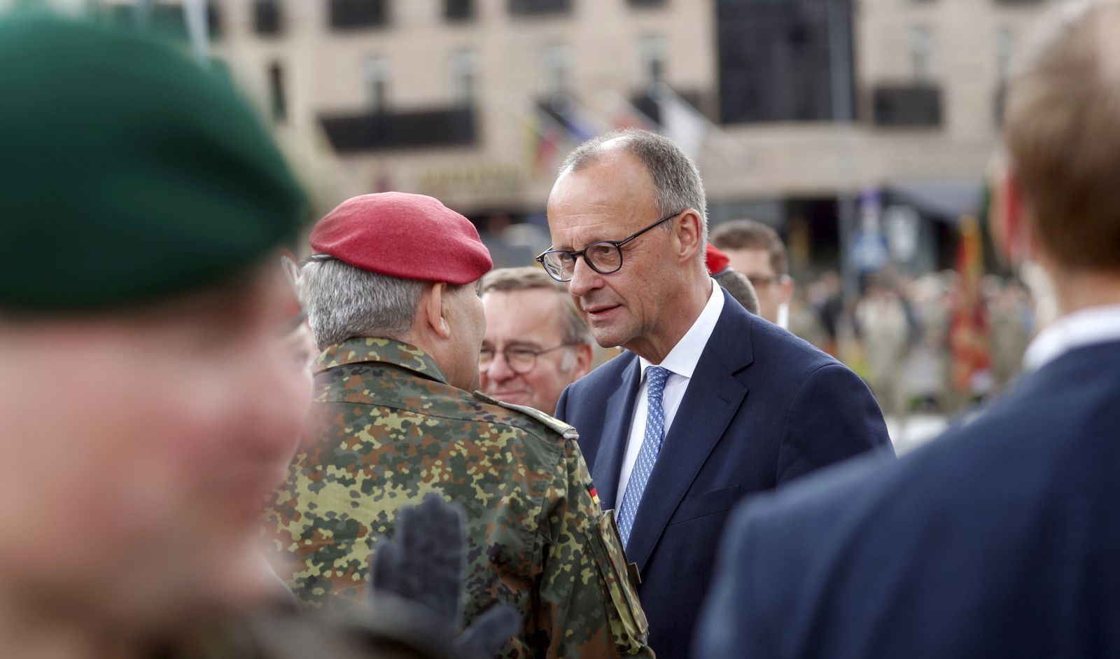 epa12125664 German Chancellor Friedrich Merz (R) greets participants during the inauguration of the German 45th Armoured Brigade 'Lithuania', at the Cathedral Square in Vilnius, Lithuania, 22 May 2025. The Brigade in Lithuania was activated on 01 April 2025, and will comprise around 5,000 military and civilian Bundeswehr personnel, with a full operational combat capability expected to be achieved by 2027.  EPA/TOMS KALNINS