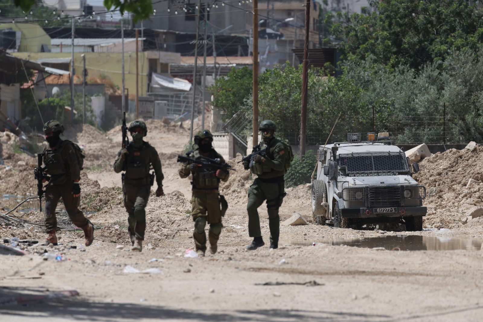 epa12136439 Israeli soliders on guard as Palestinians try to reach their houses to take care of their belongings at Tulkarem refugee camp near the West Bank city of Tulkarem, 26 May 2025.  EPA/ALAA BADARNEH