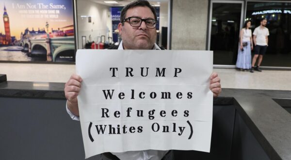 A protestor holds up a sign protesting President Trumps new policies towards refugees at the International Arrivals Terminal at Dulles International Airport as the first flight of Afrikaners From South Africa granted refugee status arrive in the United States on May 12, 2025 in Sterling, Virginia. The newly arriving Afrikaner immigrants underwent immigration processes that were expedited due to claims of oppression and genocide as the Trump administration halted immigration from other countries in the world affected by war or harsh socio-econiomic conditions. Photo by Jemal Countess/UPI Photo via Newscom Photo: Jemal Countess/NEWSCOM