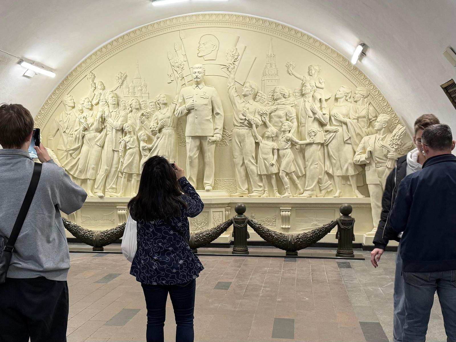 15 May 2025, Russia, Moskau: People stand in front of a relief in Moscow. More than half a century after its demolition, the city administration has had a controversial relief depicting Soviet dictator Josef Stalin recreated in the Moscow metro. The monument entitled "Gratitude of the People to the Leader and Warlord" at Taganskaya station on the brown ring line with the number 5 was demolished in the mid-1960s - in the course of de-Stalinization. Now the city has had the work of socialist realism recreated and inaugurated on the 90th anniversary of the metro, which was officially put into operation on May 15, 1935. Photo: Ulf Mauder/dpa Photo: Ulf Mauder/DPA