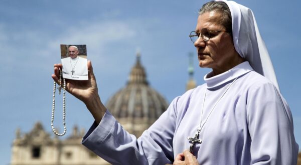 epa12044119 A nun carries a cross and a picture of Pope Francis as she prays in St. Peter's Square following the death of Pope Francis, Vatican City, 21 April 2025. Pope Francis died on 21 April 2025 at the age of 88, according to the Holy See. Born Jorge Mario Bergoglio in Buenos Aires, Argentina, on 17 December 1936, he was appointed leader of the Catholic Church on 13 March 2013, succeeding Pontiff Emeritus Benedict XVI.  EPA/ANGELO CARCONI