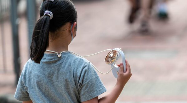 A girl uses a USB fan to cool herself in Quarry Bay as an amber alert for extreme heat is issued. The Hong Kong Observatory recently launched a new weather alert system to warn residents about the health risks of extreme heat, advising them to seek shelter and drink more water. (Photo by Ben Marans / SOPA Images/Sipa USA) Photo: SOPA Images/SIPA USA