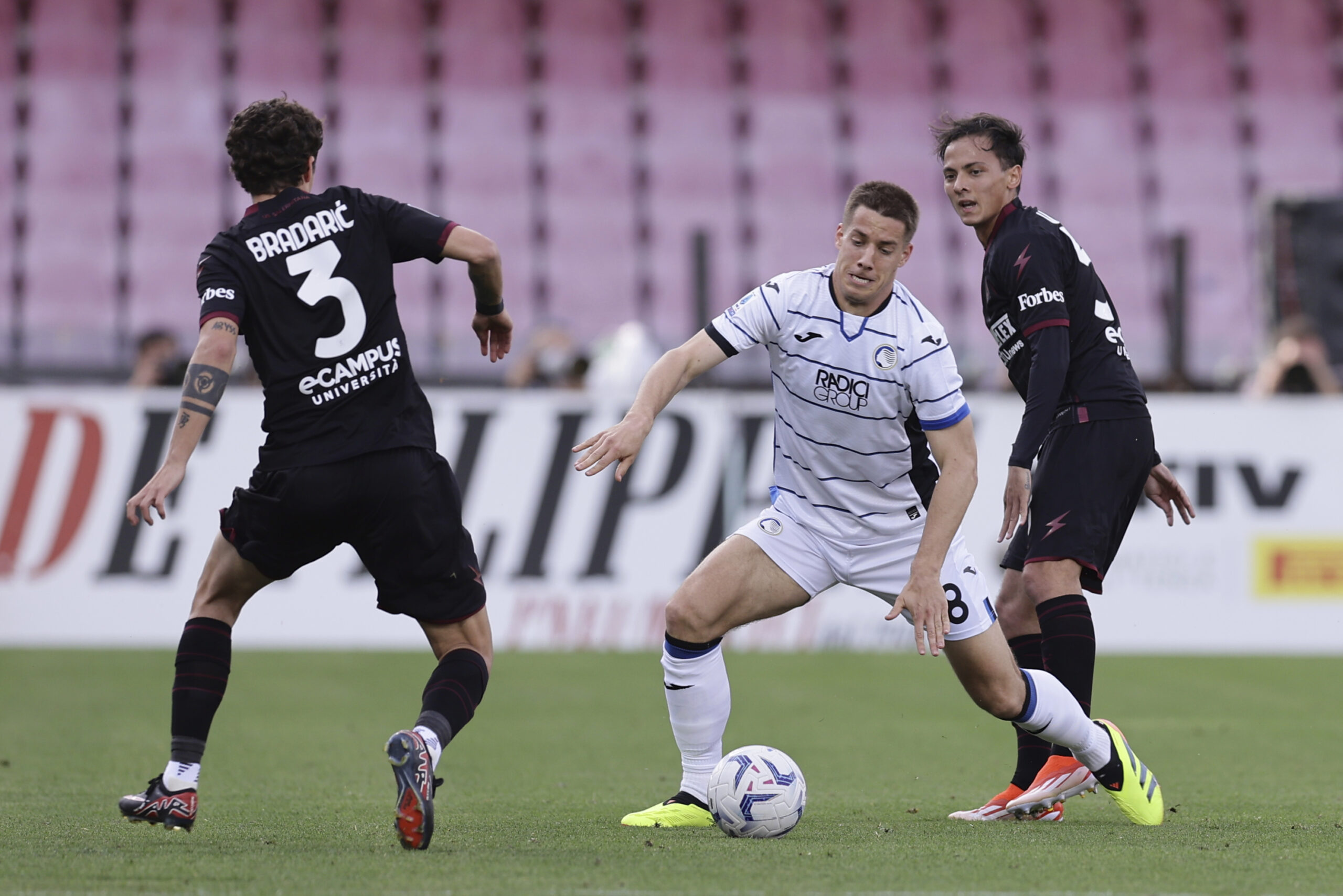 Atalanta's Mario Pasalic, centre, challenges for the ball with Salernitana's Domagoj Bradaric, left, during the Serie A soccer match between Salernitana and Atalanta at the Stadio Arechi in Salerno, Italy, Monday, May 6, 2024. (Alessandro Garofalo/LaPresse via AP)