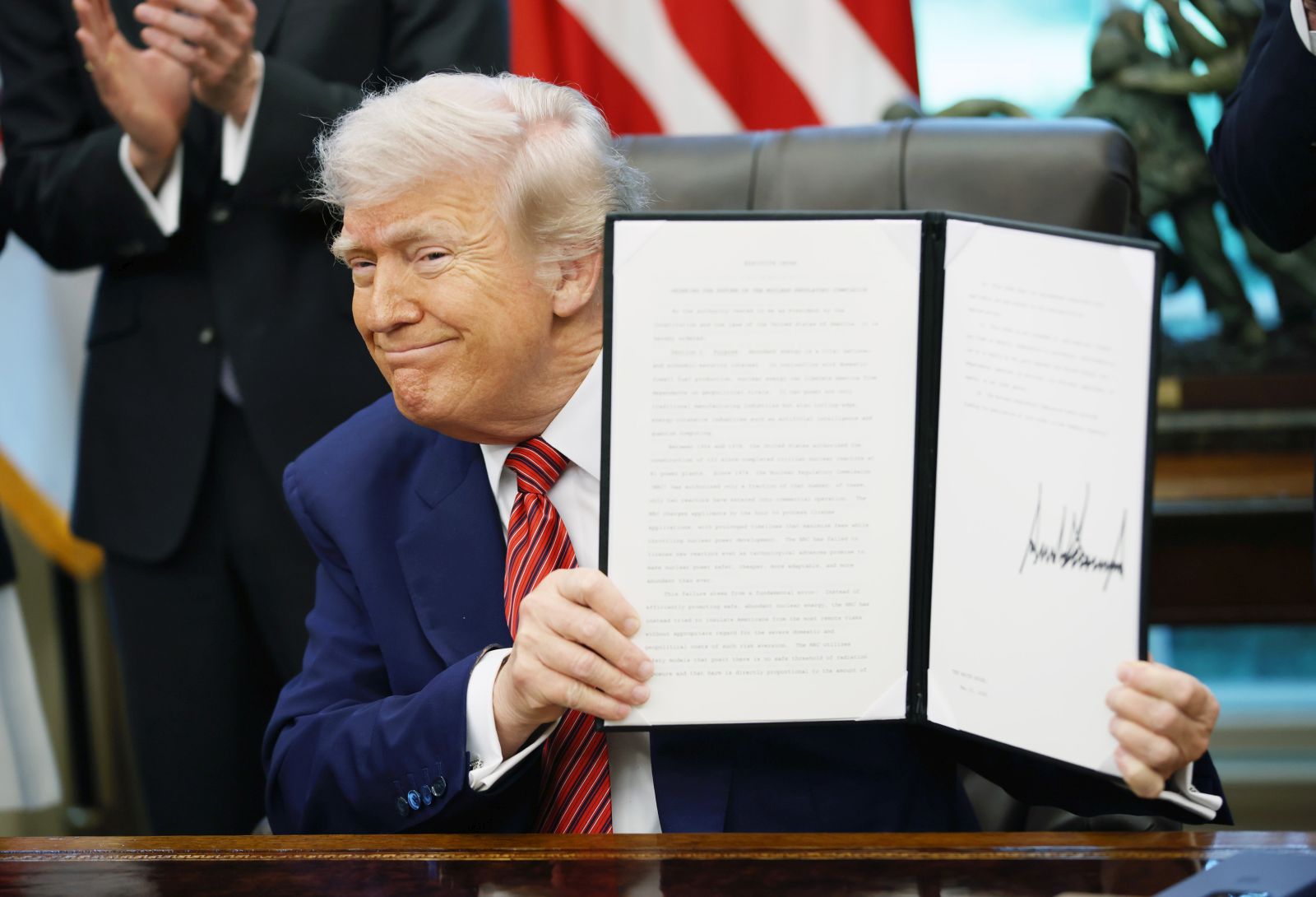 epa12129257 US President Donald Trump holds up an executive order on nuclear energy in the Oval Office of the White House, Washington, D.C., USA, 23 May 2025. He signed a total of five executive orders aimed at easing restrictions and expanding the nuclear energy industry.  EPA/SAMUEL CORUM / POOL