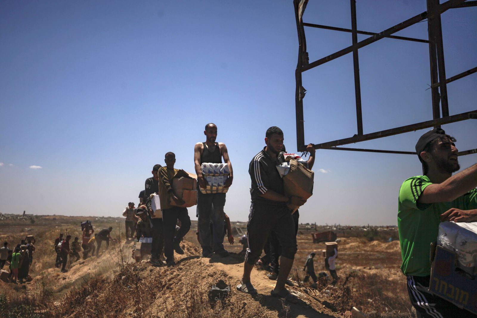 epa12143228 Palestinians carry aid supplies received from the US-backed Gaza Humanitarian Foundation through an area known as the Netzarim Corridor, central Gaza Strip, 29 May 2025. According to the UN half a million people, or one in five people in the Strip are facing starvation while the entire population of the Gaza Strip continues to face a critical risk of famine following 19 months of conflict, mass displacement and severe restrictions on humanitarian aid.  EPA/HAITHAM IMAD