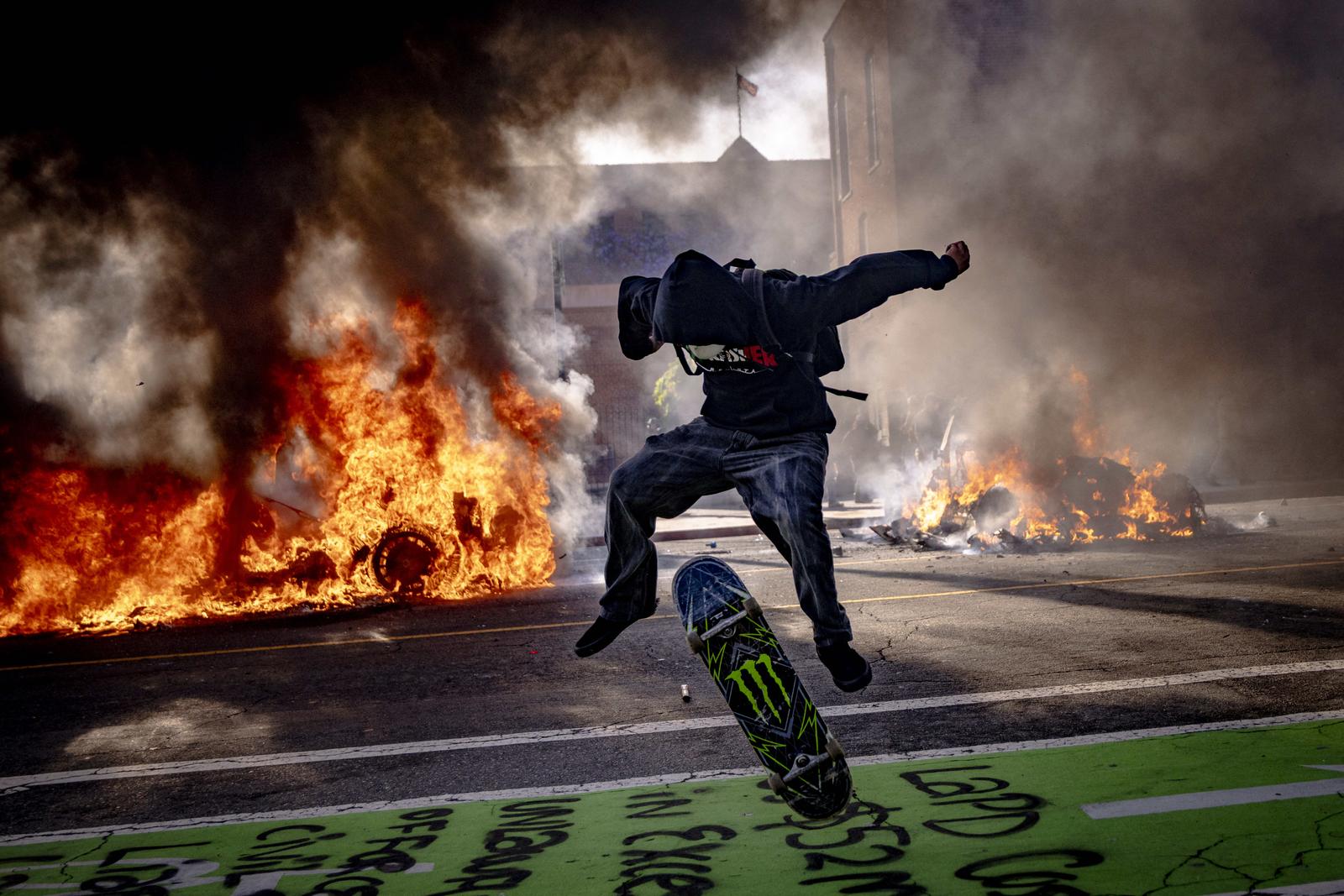 A protester leaps on a skateboard while two Waymo self-driving cars burn in the background and people continue their anti-ICE demonstrations in Los Angeles, California, on Sunday June 8, 2025. Protests erupted earlier on Friday when ICE Federal agents arrested immigrants in LA's fashion district, in a Home Depot parking lot, and several other locations. Photo by Sahab Zaribaf/Middle East Images/ABACAPRESS.COM Photo: Middle East Images/ABACA/ABACA