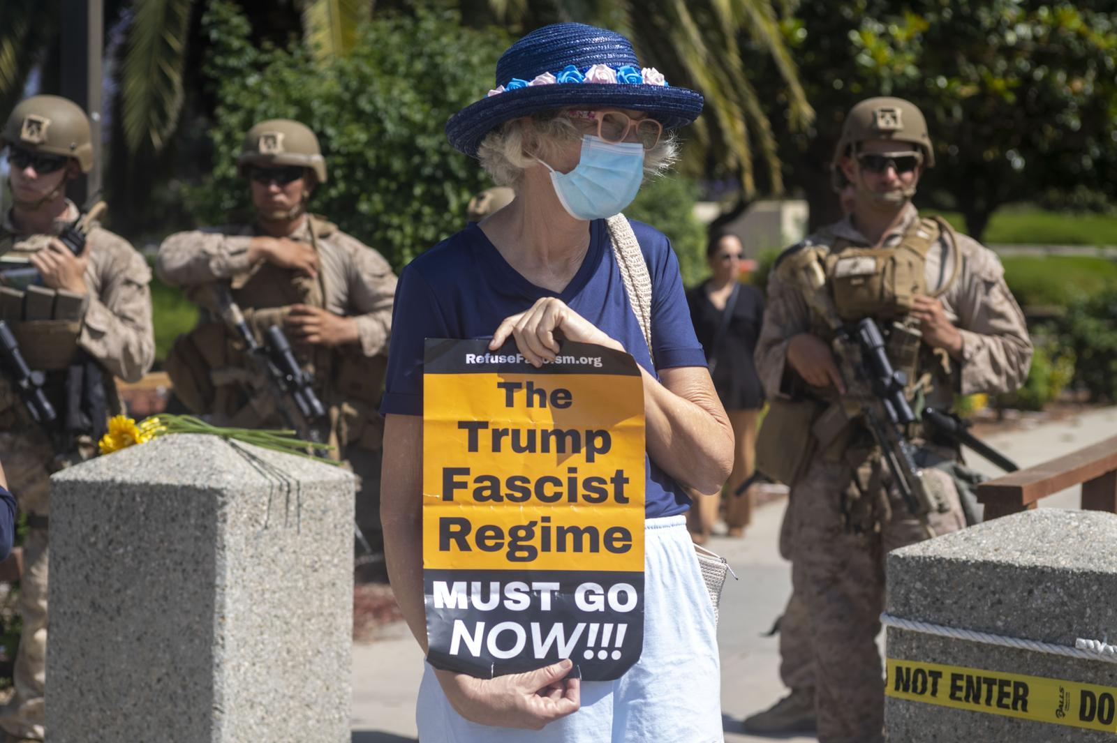 A woman holds an anti Trump placard as U.S Marines stand guard outside of a federal building. A federal appeals court ruled on June 12 that the Trump administration can maintain control of the California National Guard overturning a lower court ruling that U.S. President Donald Trump's deployment of troops without Governor Gavin Newsom's consent is unlawful. (Photo by Ringo Chiu / SOPA Images/Sipa USA) Photo: SOPA Images/SIPA USA