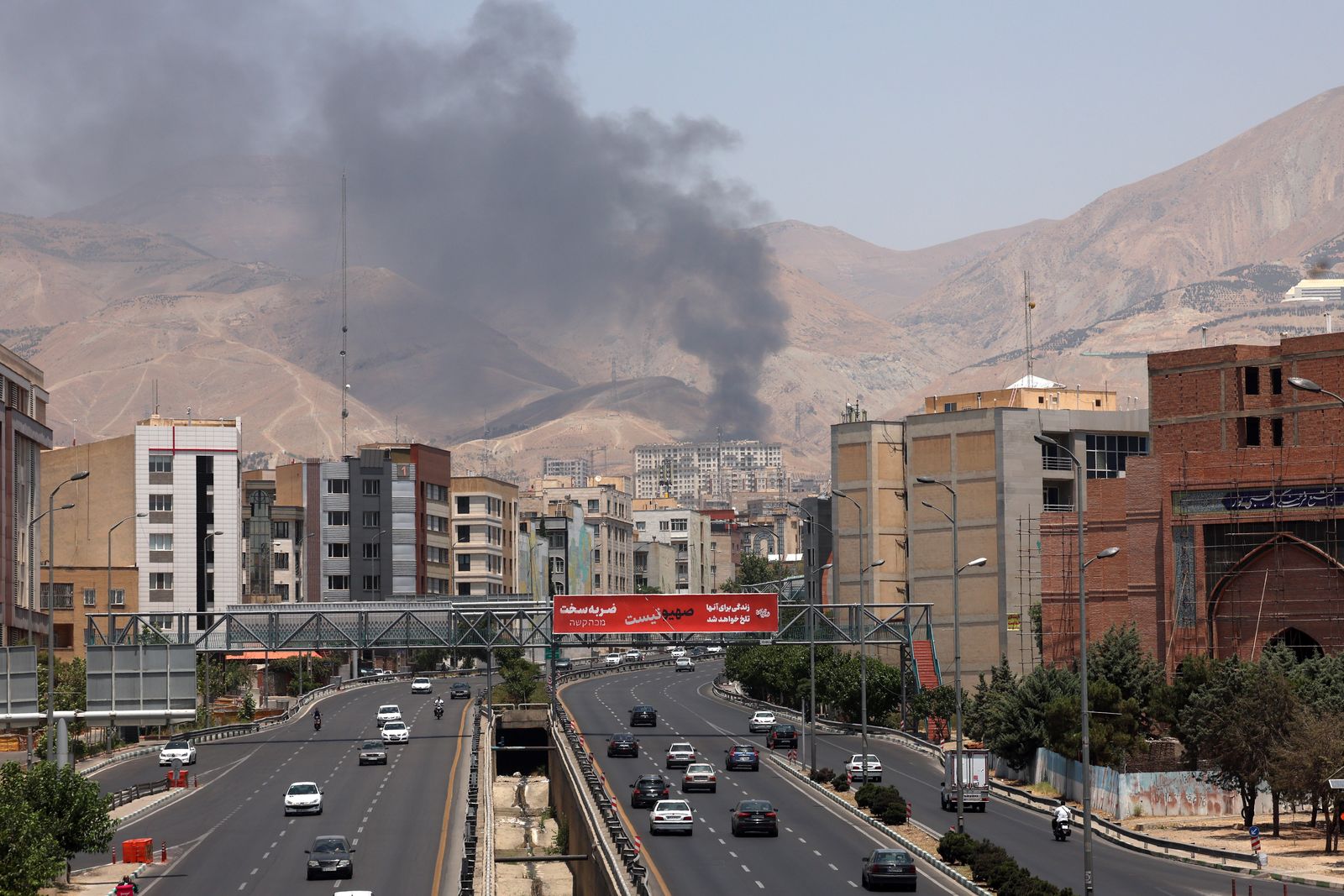epa12178551 Cars drive along a motorway as smoke rises in the background from an oil refinery, northwest of Tehran, Iran, 16 June 2025. Israel and Iran have been exchanging fire since Israel launched strikes across Iran on 13 June 2025 as part of Operation 'Rising Lion.'  EPA/ABEDIN TAHERKENAREH