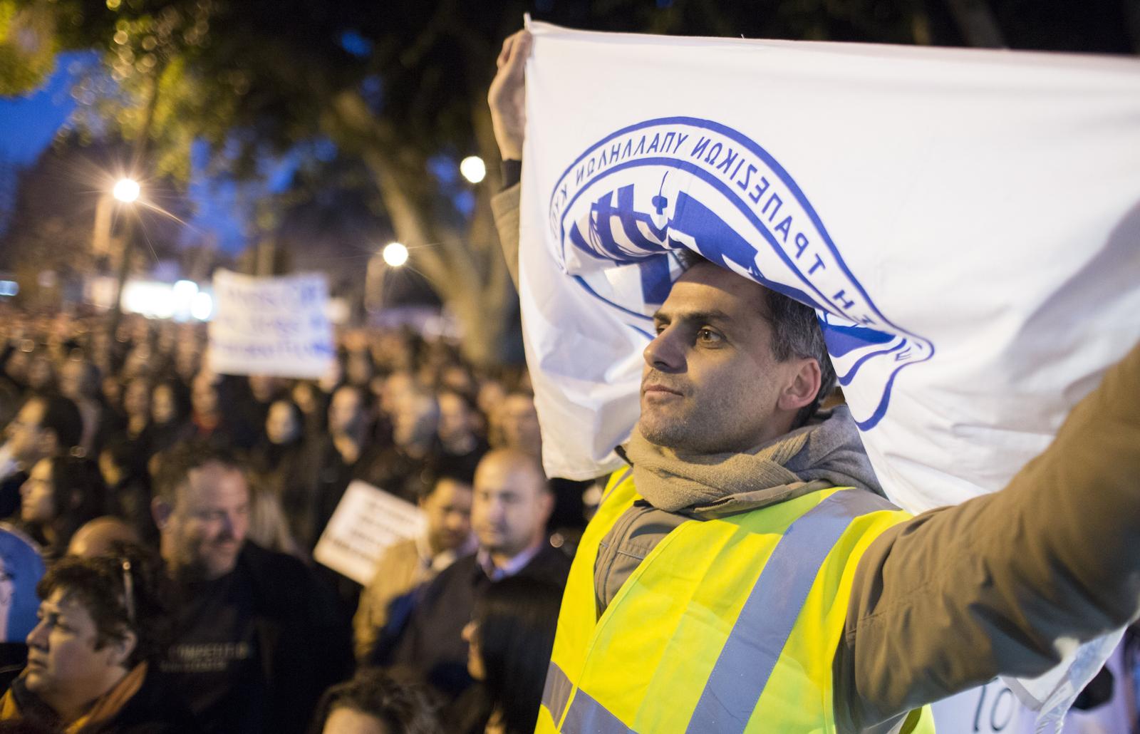 A man holds a banner with the logo of the trade union of bank employees of Cyprus (ETYK) in Nikosia, Cyprus, 23 March 2013. Discussions continue on Cyprus for a way out of the country's crisis. Photo:
