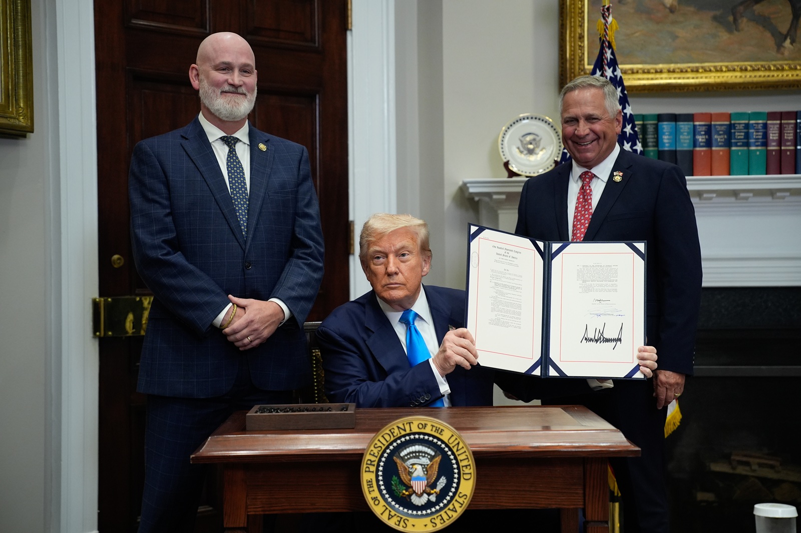 epa12273463 US President Donald Trump (C), flanked by US Representatives Derrick Van Orden (Republican from Wisconsin) and Mike Bost (Republican from Illinois), shows the signed Congressional Bill in the Roosevelt Room at the White House in Washington, SC, USA, 30 July 2025.  EPA/YURI GRIPAS / POOL