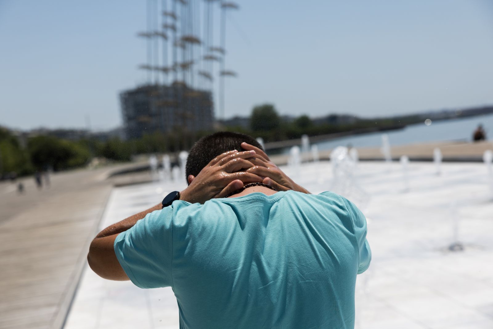 epa12222209 A man cools off at a fountain on a day with very high temperatures in Thessaloniki, Greece, 07 July 2025. Very high temperatures are forecast in Greece until 09 July. The highest temperatures, exceeding 40 degrees Celsius, are predicted for mainland Greece.  EPA/ACHILLEAS CHIRAS