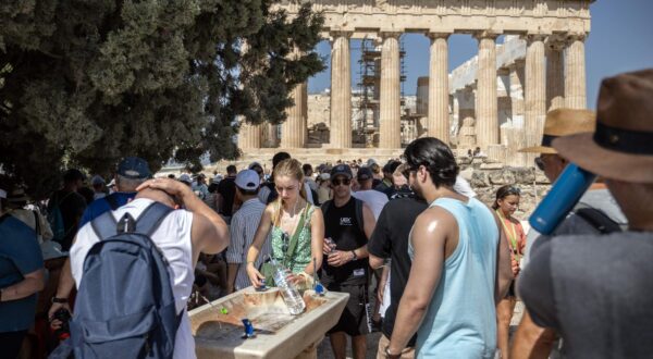 14 July 2023, Greece, Athen: Tourists cool off at a water fountain during their visit to the Parthenon Temple on the Acropolis Hill on this hot day. The Ministry of Culture has decided to close the archaeological site during the hottest hours of the day, from noon to 5 p.m., as Greece is currently experiencing a heat wave. Photo: Angelos Tzortzinis/dpa Photo: ANGELOS TZORTZINIS/DPA