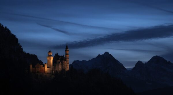 dpatop - 19 February 2025, Bavaria, Schwangau: Neuschwanstein Castle stands in front of the panorama of the Alps after sunset at the blue hour. Photo: Karl-Josef Hildenbrand/dpa Photo: Karl-Josef Hildenbrand/DPA