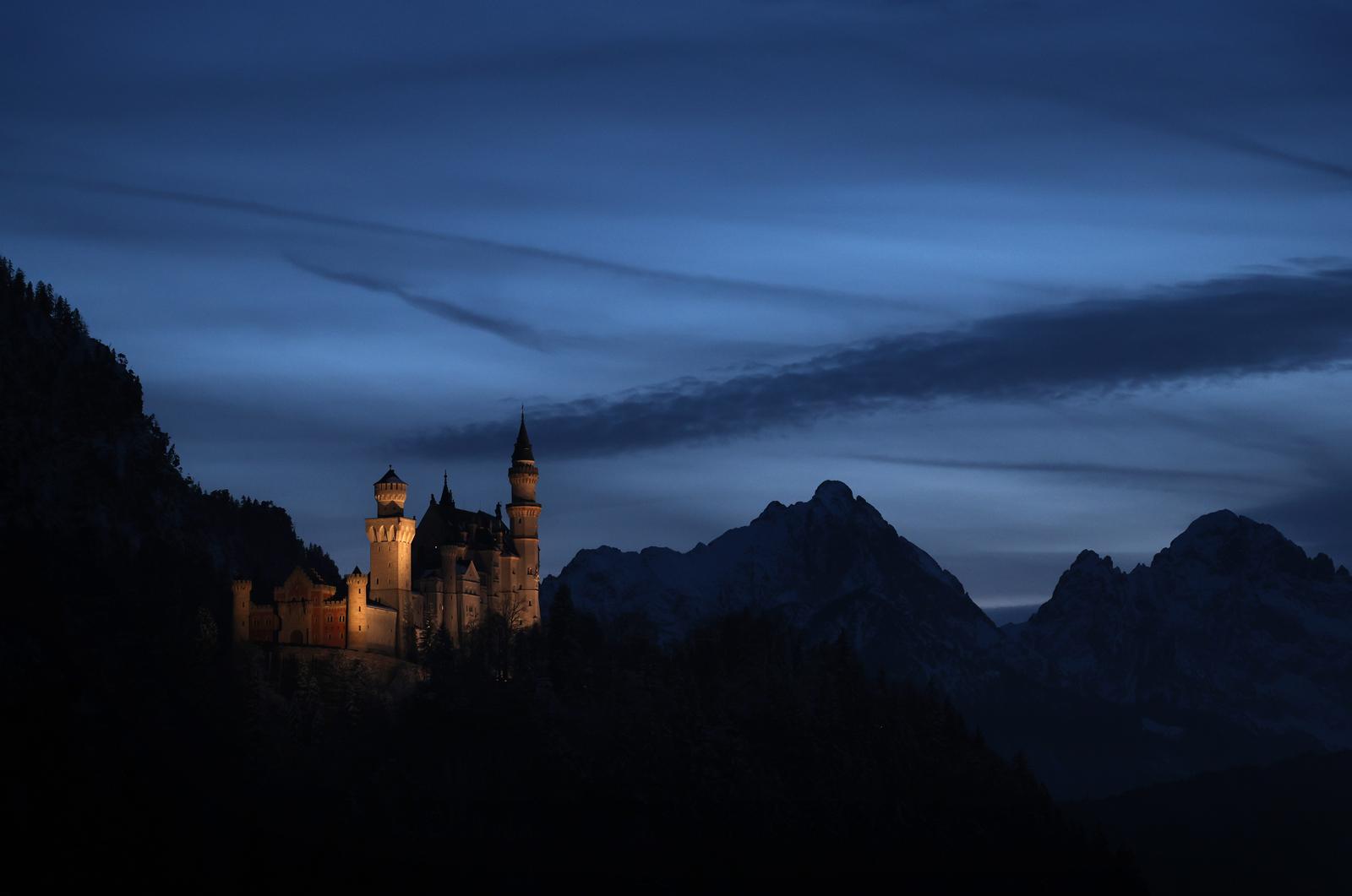 dpatop - 19 February 2025, Bavaria, Schwangau: Neuschwanstein Castle stands in front of the panorama of the Alps after sunset at the blue hour. Photo: Karl-Josef Hildenbrand/dpa Photo: Karl-Josef Hildenbrand/DPA