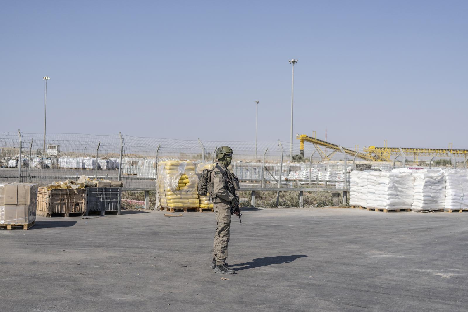 24 July 2025, Palestinian Territories, Kerem Shalom: An Israeli soldier stands beside humanitarian aid packages awaiting pickup on the Palestinian side of the Kerem Shalom crossing in the Gaza Strip during a media tour organized by the Israeli army. Photo: Ilia Yefimovich/dpa Photo: ILIA YEFIMOVICH/DPA