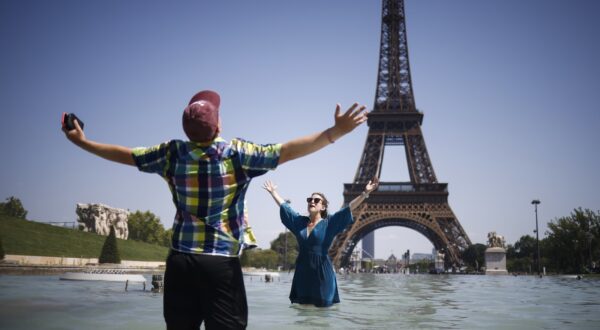 epa12208719 People cool off with water from Varsovie fountain by the Eiffel Tower during a heatwave in Paris, France, 01 July 2025. The hottest day of this heatwave on 01 July 2025, will register temperatures peaking into 40-41 degrees Celsius, in several departments, according to Meteo France.  EPA/YOAN VALAT