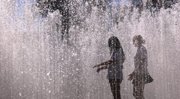 02 July 2025, Bavaria, Nuremberg: Young people walk through the water installation "Hexagonal Water Pavilion" by Danish artist Jeppe Hein in front of the Neues Museum. The installation in the form of a walk-in fountain is a popular way to cool off in summer temperatures. Photo: Daniel Karmann/dpa Photo: Daniel Karmann/DPA