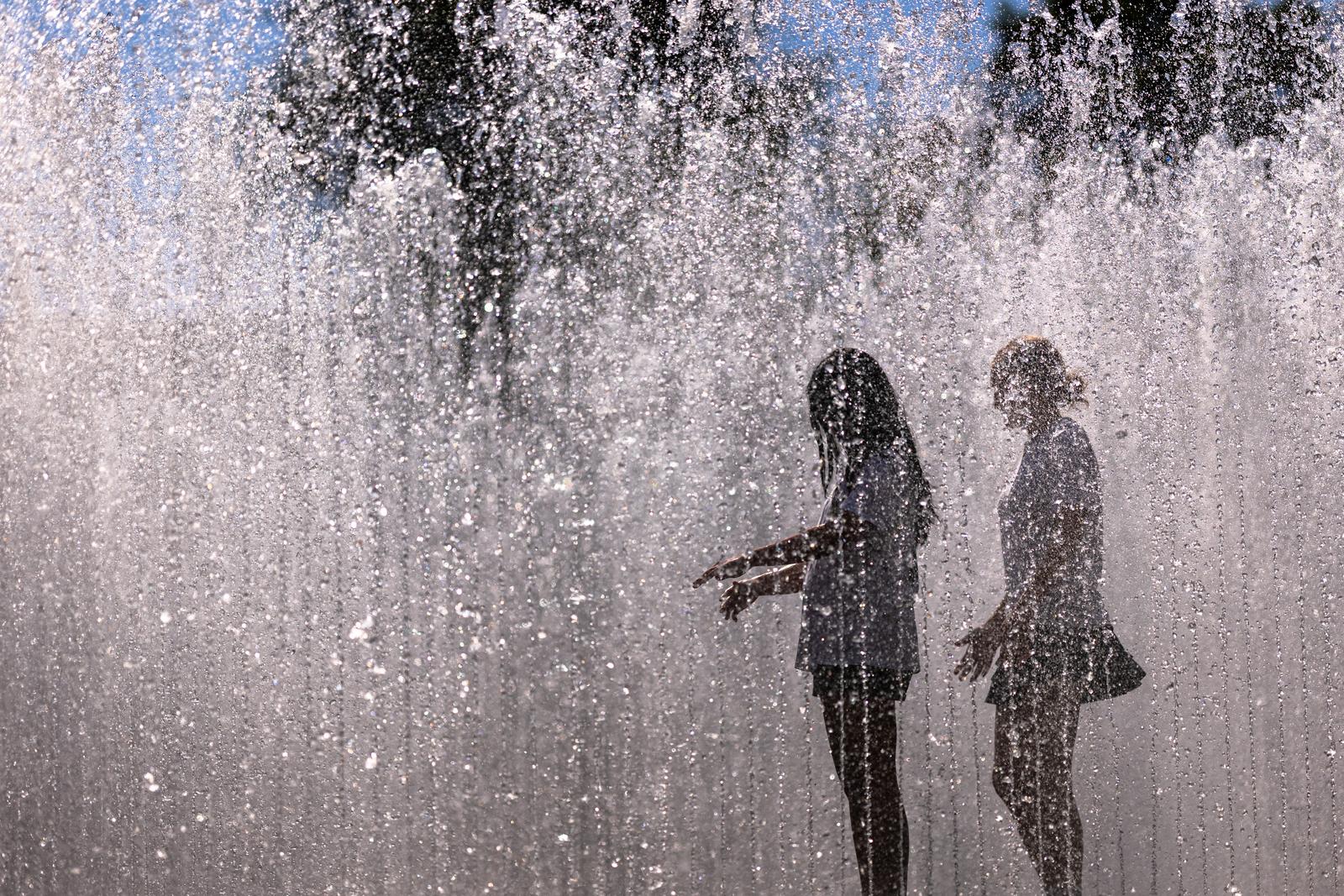 02 July 2025, Bavaria, Nuremberg: Young people walk through the water installation "Hexagonal Water Pavilion" by Danish artist Jeppe Hein in front of the Neues Museum. The installation in the form of a walk-in fountain is a popular way to cool off in summer temperatures. Photo: Daniel Karmann/dpa Photo: Daniel Karmann/DPA
