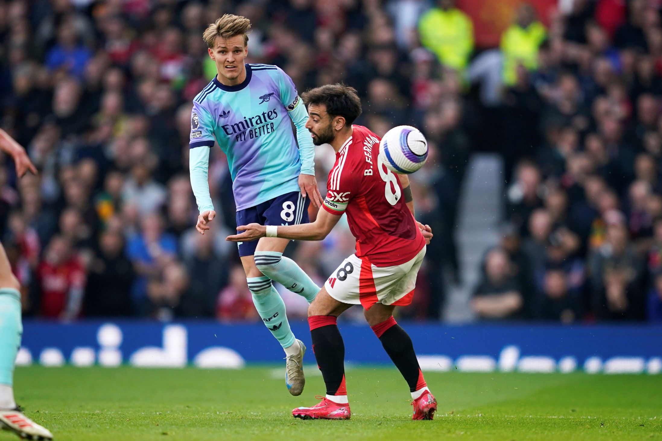 Arsenal's Martin Odegaard, left, and Manchester United's Bruno Fernandes compete for the ball during the English Premier League soccer match between Manchester United and Arsenal at Old Trafford stadium in Manchester, England, Sunday, March 9, 2025. (AP Photo/Dave Thompson) Britain Soccer Premier League