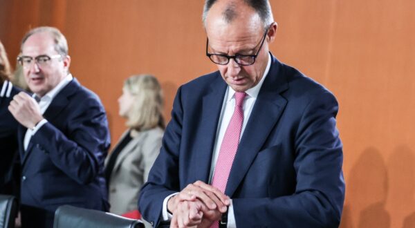 epa12255183 German Chancellor Friedrich Merz (R) checks his watch as he attends the federal cabinet meeting at the Chancellery in Berlin, Germany, 23 July 2025.  EPA/FILIP SINGER