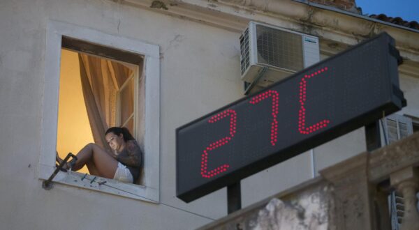 12.07.2015., Split - Uvecer kada temperature barem malo padnu mnogi se turisti kao i domaci ljudi odluce na setnju Marmontovom ulicom u Splitu. Djevojka na prozoru cita s mobitela dok panel za mjerenje temperature pokazuje 27 stupnjeva celziusa.r"n Photo: Davor Puklavec/PIXSELL
