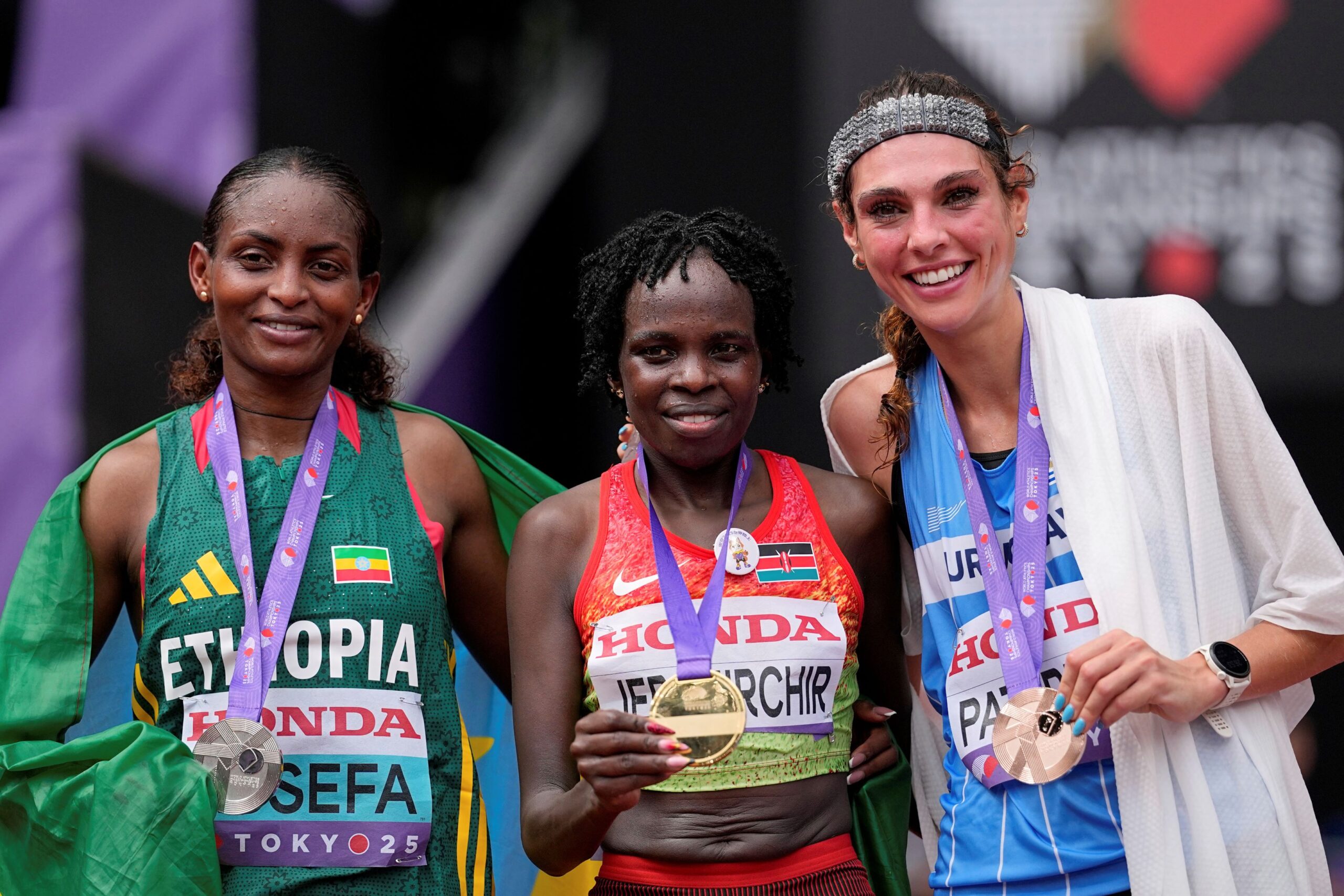 Gold medalist Kenya's Peres Jepchirchir, center, poses with silver medalist Ethiopia's Tigst Assefa and bronze medalist Uruguay's Julia Paternainafter finishing the women's marathon at the World Athletics Championships in Tokyo, Sunday, Sept. 14, 2025. (AP Photo/Matthias Schrader) Japan Athletics Worlds
