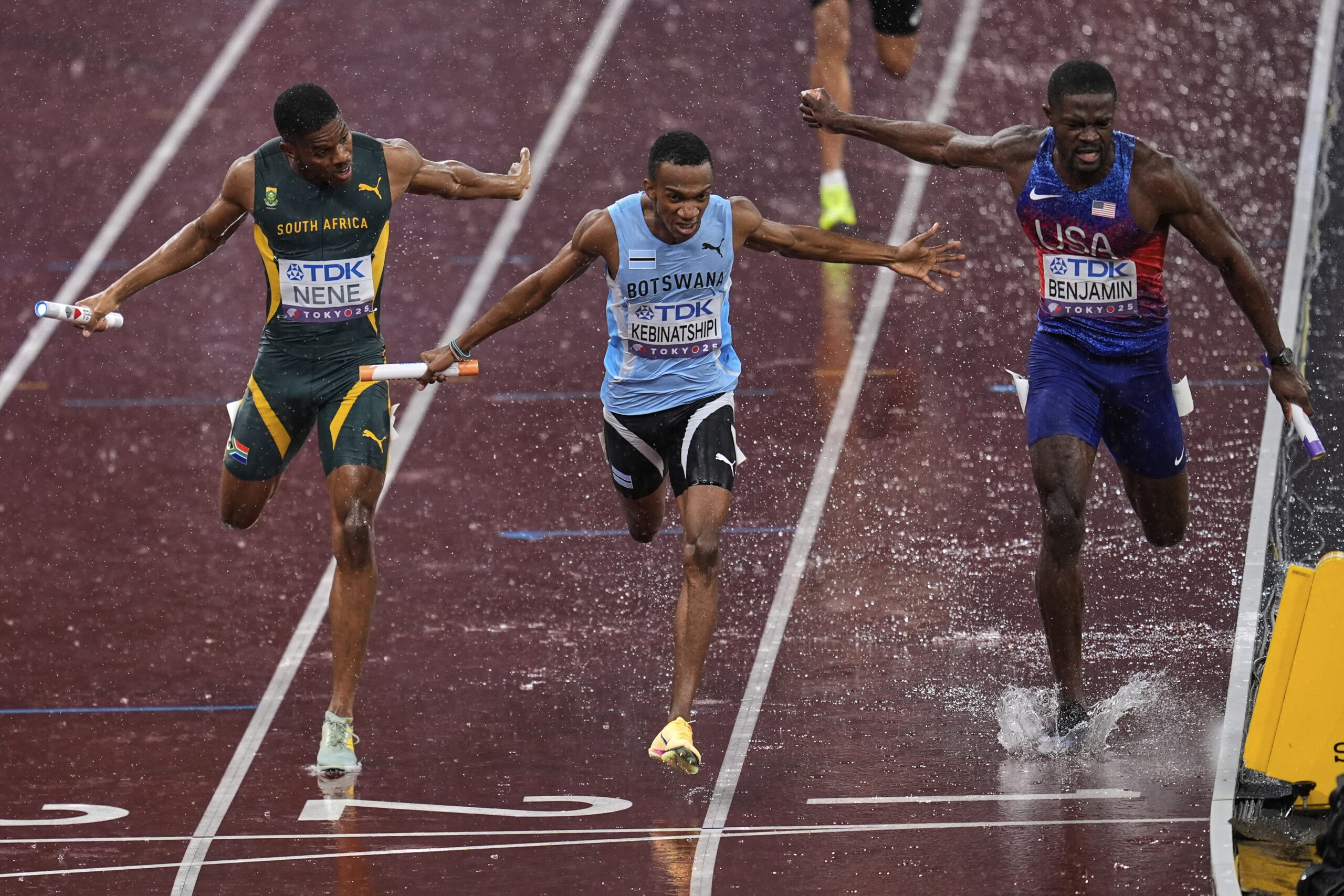 Botswana's Busang Collen Kebinatshipi crosses the finish line before United States' Rai Benjamin and South Africa's Zakithi Nene in the men's 4 X 400 meters relay final at the World Athletics Championships in the rain in Tokyo, Sunday, Sept. 21, 2025. (AP Photo/Abbie Parr)