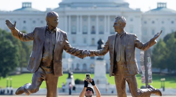 UNITED STATES - SEPTEMBER 23: A cyclist stops to take photos of a statue featuring President Donald Trump and Jeffrey Epstein dancing, titled In Honor of Friendship Month, that appeared on the east end of the National Mall in Washington on Tuesday morning, September 23, 2025. (Bill Clark/CQ Roll Call/Sipa USA) Photo: CQ-Roll Call/SIPA USA