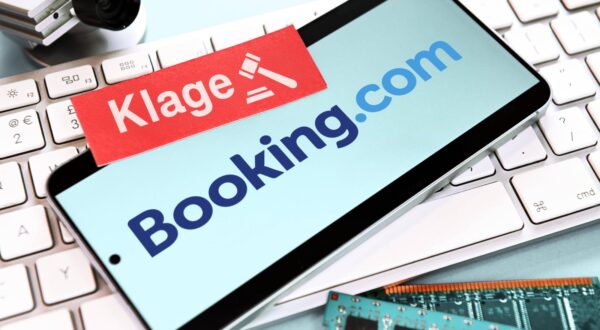FOTOMONTAGE, Smartphone mit Schriftzug von Booking.com und Zettel mit Aufschrift Klage auf einer Computertastatur, Klage von Hotelbetreibern gegen das Reiseportal *** PHOTOMONTAGE, smartphone with Booking com lettering and note with the word Klage on a computer keyboard, lawsuit by hotel operators against the travel portal Photo: IMAGO/Christian Ohde/IMAGOSTOCK&PEOPLE