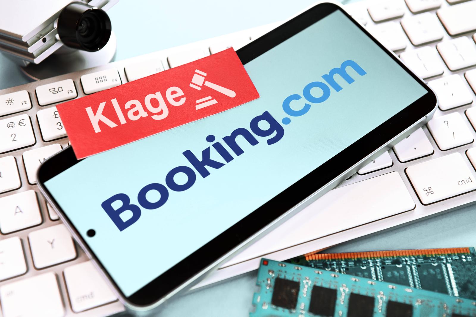 FOTOMONTAGE, Smartphone mit Schriftzug von Booking.com und Zettel mit Aufschrift Klage auf einer Computertastatur, Klage von Hotelbetreibern gegen das Reiseportal *** PHOTOMONTAGE, smartphone with Booking com lettering and note with the word Klage on a computer keyboard, lawsuit by hotel operators against the travel portal Photo: IMAGO/Christian Ohde/IMAGOSTOCK&PEOPLE
