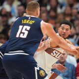 Phoenix Suns guard Devin Booker, right, is trapped with the ball by Denver Nuggets center Nikola Jokic (15) and forward Christian Braun, back left, in the second half of an NBA basketball game Saturday, Oct. 25, 2025, in Denver. (AP Photo/David Zalubowski)