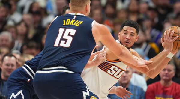 Phoenix Suns guard Devin Booker, right, is trapped with the ball by Denver Nuggets center Nikola Jokic (15) and forward Christian Braun, back left, in the second half of an NBA basketball game Saturday, Oct. 25, 2025, in Denver. (AP Photo/David Zalubowski)