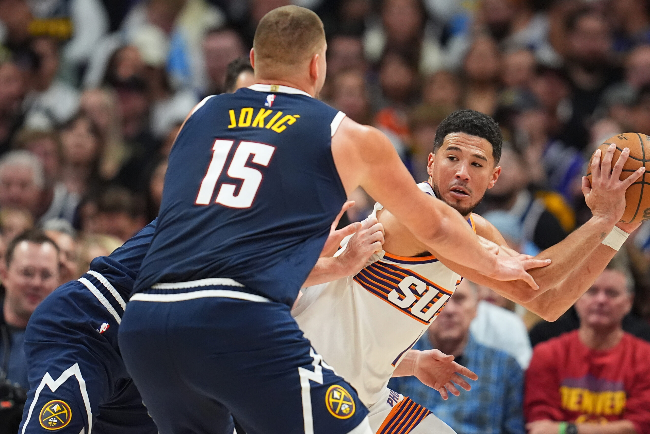 Phoenix Suns guard Devin Booker, right, is trapped with the ball by Denver Nuggets center Nikola Jokic (15) and forward Christian Braun, back left, in the second half of an NBA basketball game Saturday, Oct. 25, 2025, in Denver. (AP Photo/David Zalubowski)