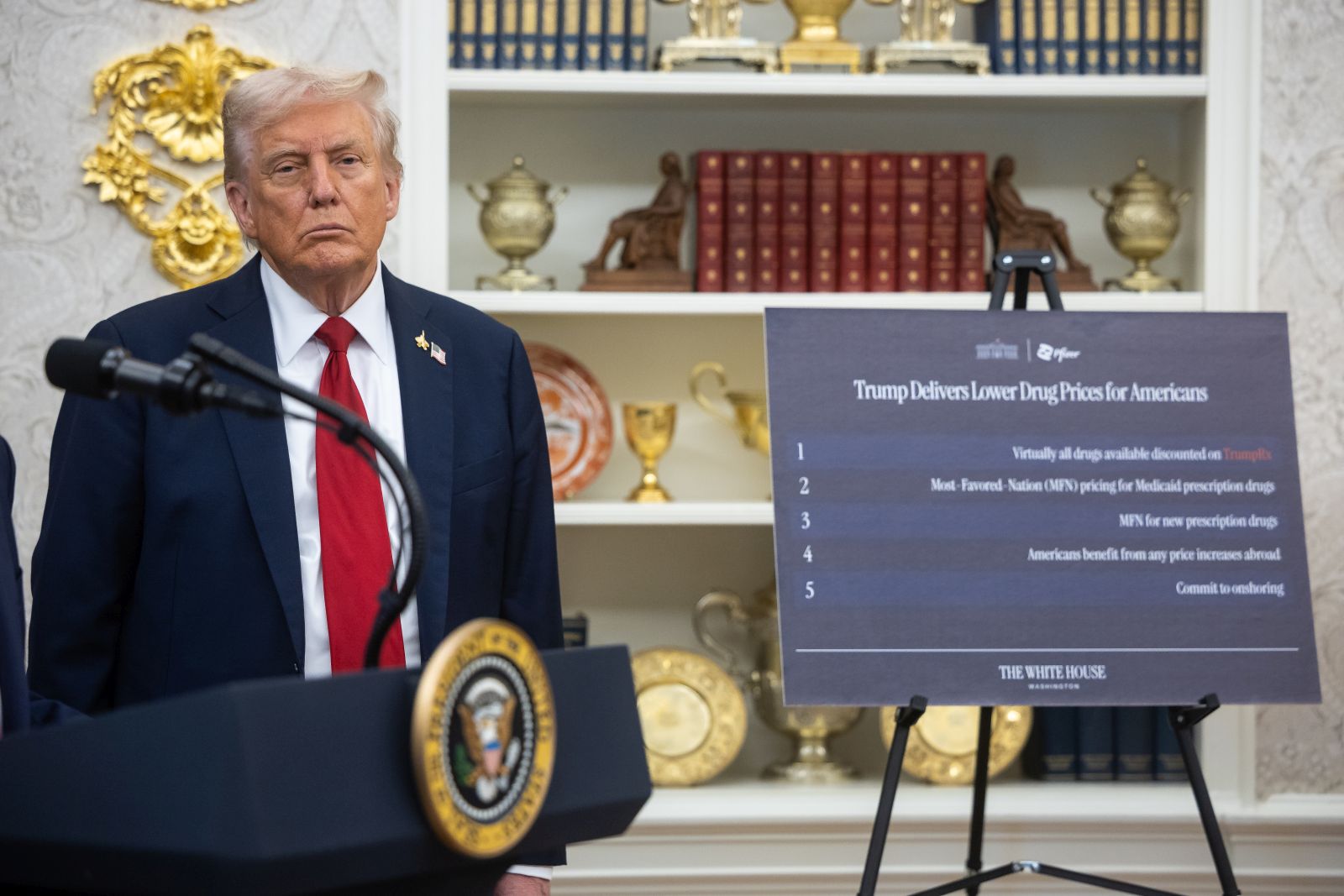 epa12417475 US President Donald Trump stands near a sign on lowering drug prices for Americans as he announces a drug-pricing deal with Pfizer in the Oval Office at the White House in Washington, DC, USA, 30 September 2025.  EPA/FRANCIS CHUNG / POOL