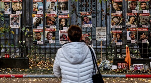 epa12451253 A pedestrian looks on at portraits of Israeli hostages and victims displayed on a fence in front of the New Synagogue in Berlin, Germany, 13 October 2025. The first phase of the Gaza peace agreement, reached between Israel and Hamas, includes the release of Israeli hostages and Palestinian prisoners, a partial withdrawal of Israeli forces, and the delivery of humanitarian aid to Gaza.  EPA/FILIP SINGER